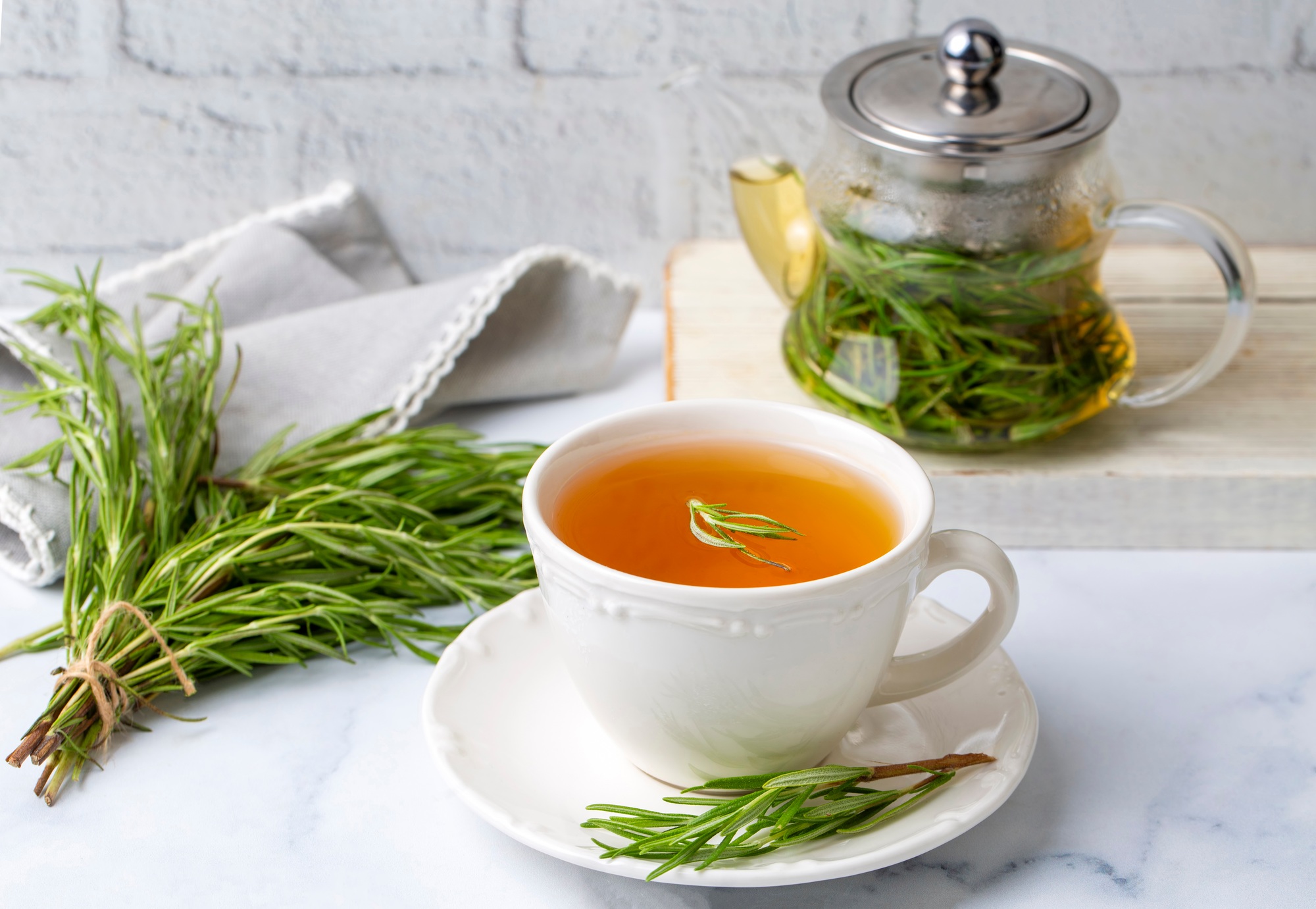Cup of healthy rosemary tea with fresh rosemary bunch winter herbal hot drink concept,
